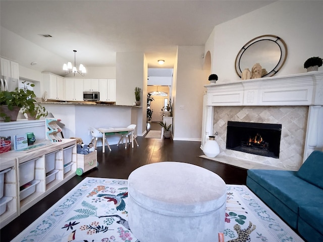 living room featuring a tiled fireplace, dark hardwood / wood-style flooring, lofted ceiling, and a chandelier