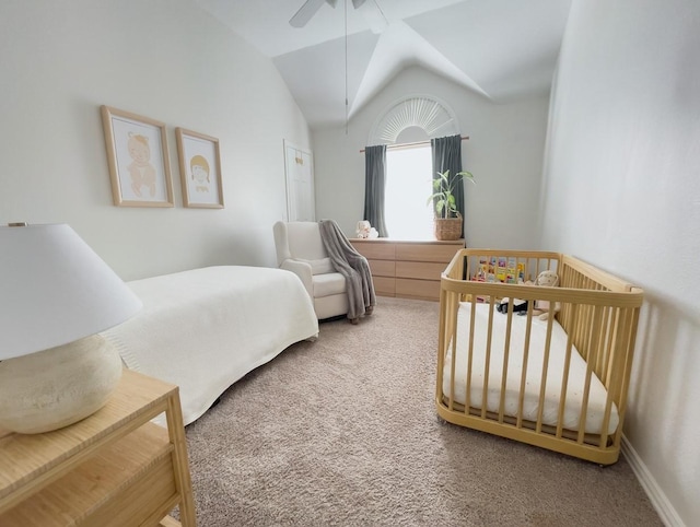 carpeted bedroom with lofted ceiling, a crib, and ceiling fan