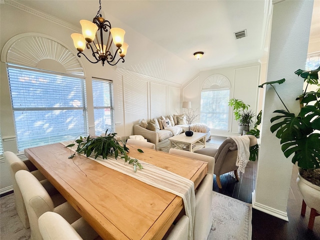 dining space featuring an inviting chandelier, vaulted ceiling, crown molding, and hardwood / wood-style flooring