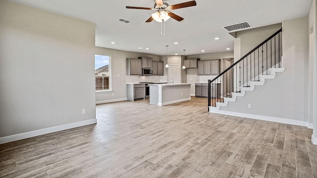 unfurnished living room featuring ceiling fan, light wood-type flooring, and sink