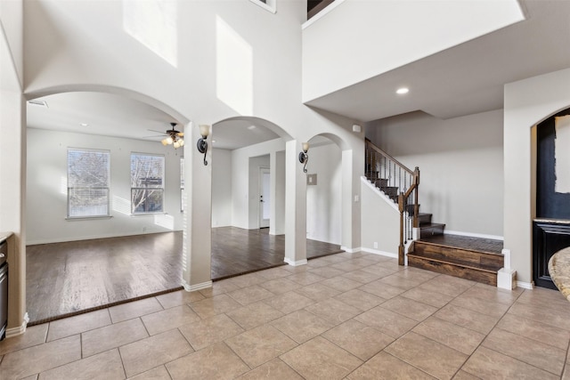 foyer entrance featuring a towering ceiling, light tile patterned flooring, and ceiling fan