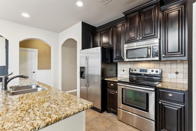 kitchen with stainless steel appliances, light stone countertops, light tile patterned flooring, and sink