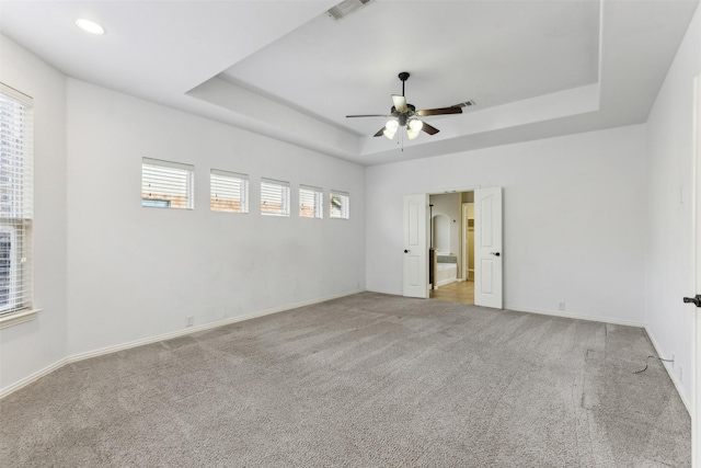 carpeted empty room with ceiling fan and a tray ceiling