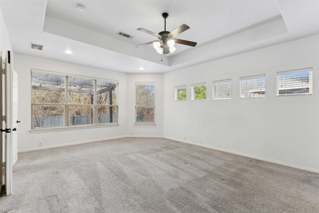 carpeted empty room with ceiling fan and a tray ceiling