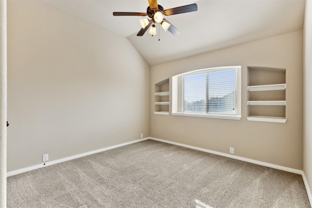 carpeted spare room with lofted ceiling, ceiling fan, and built in shelves