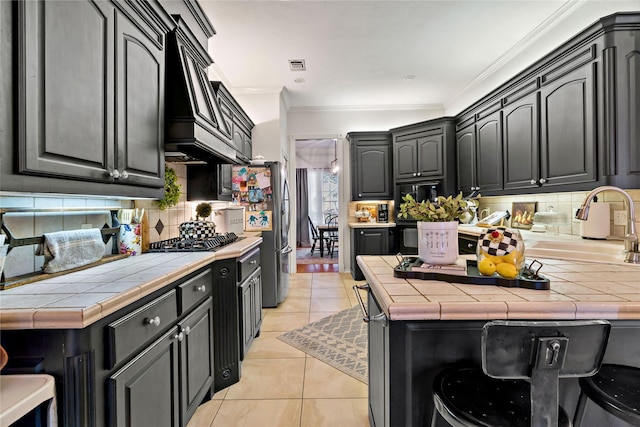 kitchen featuring custom exhaust hood, light tile patterned flooring, tasteful backsplash, and tile counters