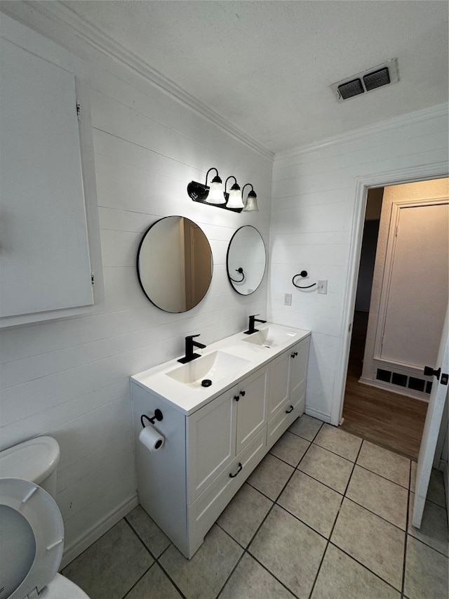 bathroom with toilet, tile patterned flooring, vanity, and crown molding