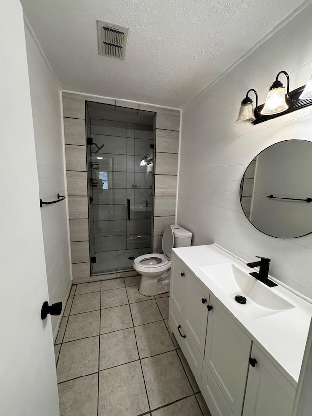 bathroom featuring toilet, tile patterned floors, vanity, a shower with door, and a textured ceiling