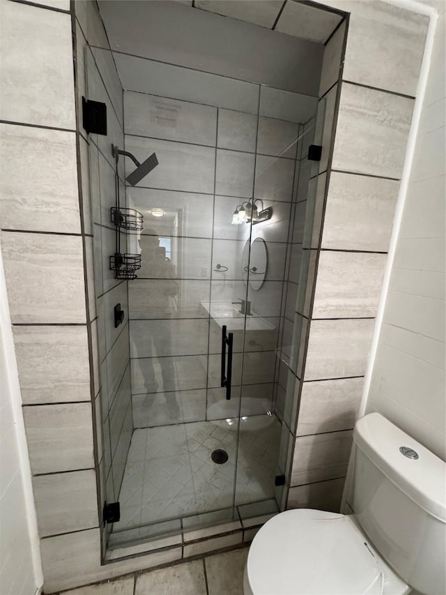 bathroom featuring toilet and a shower with door