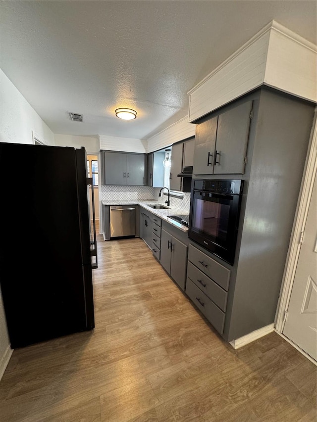 kitchen featuring black appliances, gray cabinetry, a textured ceiling, light hardwood / wood-style flooring, and sink