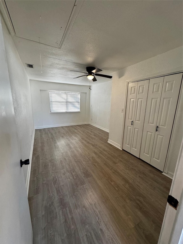 unfurnished living room featuring a textured ceiling, ceiling fan, and dark hardwood / wood-style floors