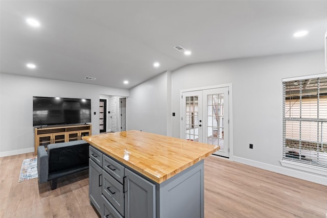 kitchen with vaulted ceiling, butcher block counters, french doors, a kitchen island, and gray cabinetry