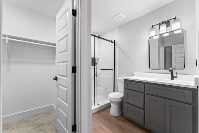 bathroom with vanity, hardwood / wood-style flooring, a shower with shower door, and toilet