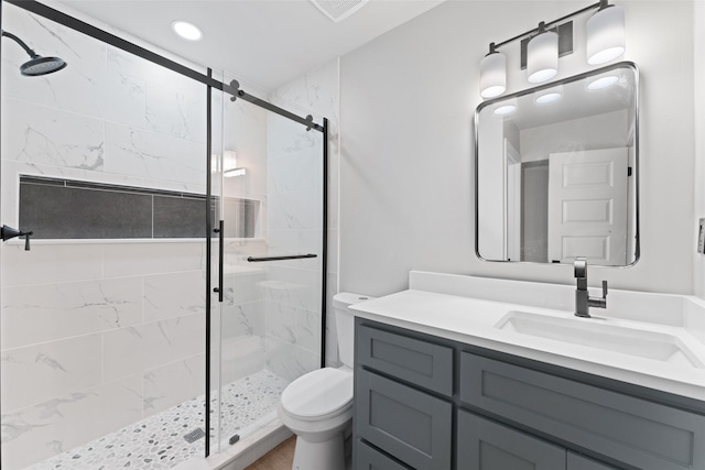 bathroom featuring toilet, vanity, and a shower with shower door