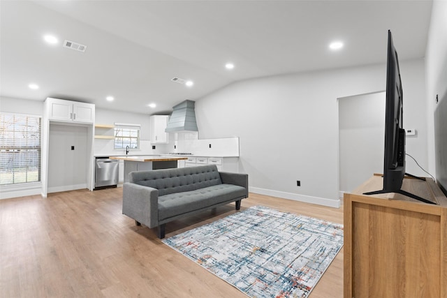 living room with light hardwood / wood-style floors, lofted ceiling, and sink