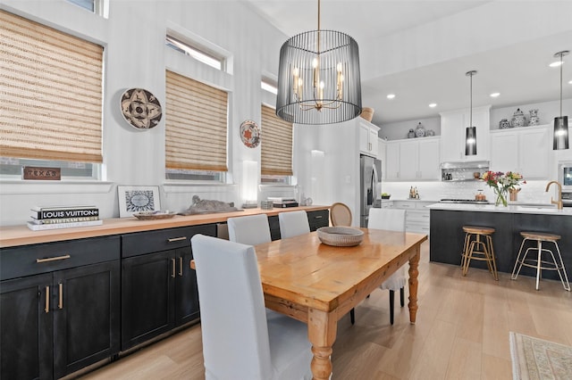 dining area featuring sink, a notable chandelier, and light hardwood / wood-style floors