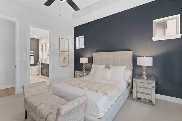 bedroom with ensuite bathroom, light colored carpet, and ceiling fan