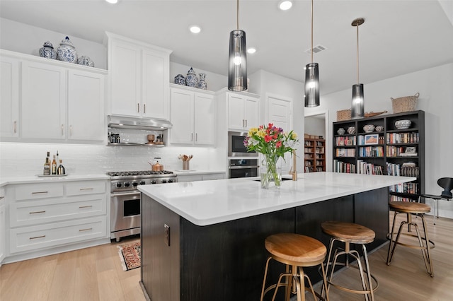 kitchen featuring white cabinetry, a center island, hanging light fixtures, light wood-type flooring, and stainless steel appliances