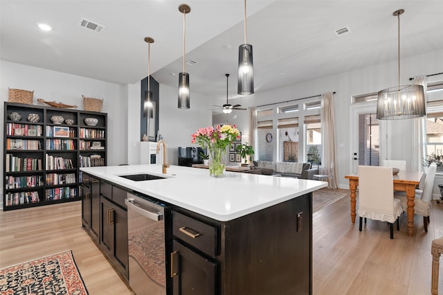 kitchen featuring sink, hanging light fixtures, a center island with sink, dishwasher, and ceiling fan with notable chandelier