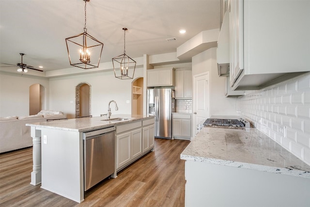 kitchen featuring decorative light fixtures, a center island with sink, decorative backsplash, appliances with stainless steel finishes, and sink