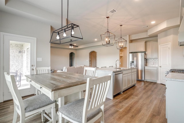 dining area with ceiling fan, light hardwood / wood-style floors, and sink