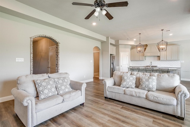 living room with sink, ceiling fan, and light wood-type flooring