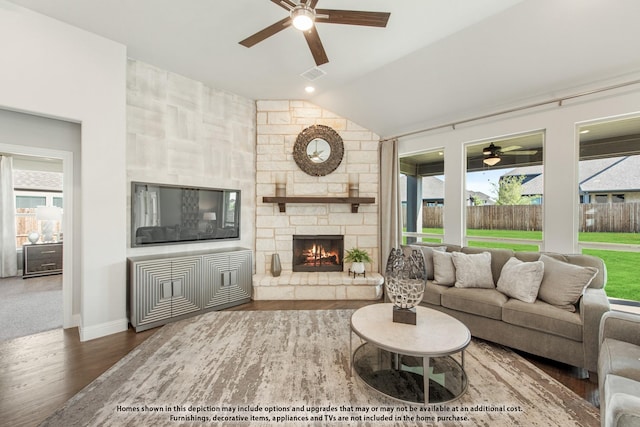 living room with dark wood-type flooring, a stone fireplace, and vaulted ceiling