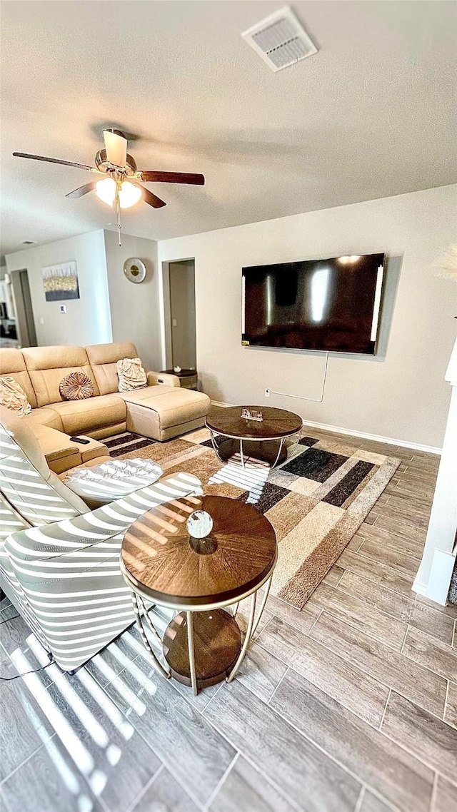 living room featuring ceiling fan and a textured ceiling