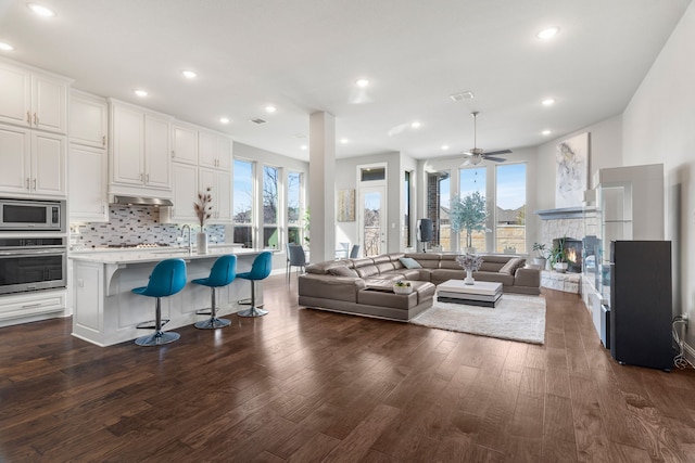 kitchen featuring stainless steel appliances, white cabinets, a kitchen bar, an island with sink, and dark hardwood / wood-style flooring