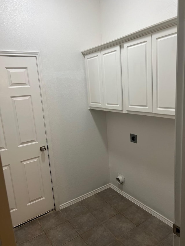 washroom featuring cabinets, hookup for an electric dryer, and dark tile patterned flooring