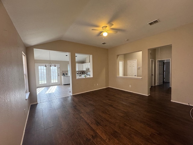 unfurnished living room featuring ceiling fan with notable chandelier, a textured ceiling, lofted ceiling, and dark hardwood / wood-style floors