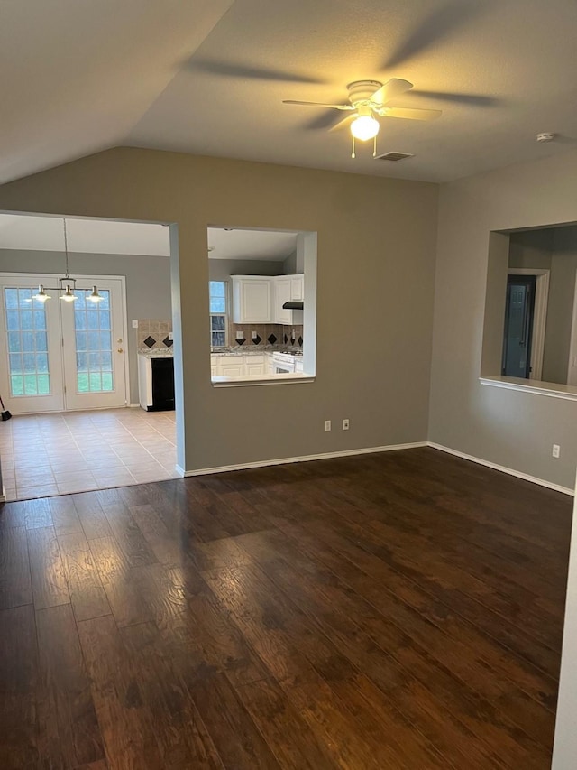 unfurnished living room featuring light wood-type flooring, vaulted ceiling, and ceiling fan with notable chandelier