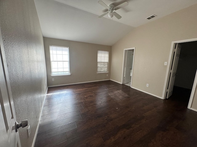 unfurnished bedroom featuring lofted ceiling, dark wood-type flooring, ceiling fan, and a spacious closet