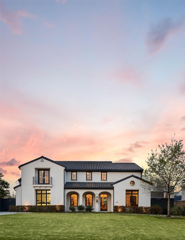 back house at dusk featuring a lawn