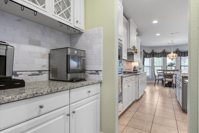 kitchen featuring decorative backsplash, white cabinetry, light tile patterned floors, and light stone counters