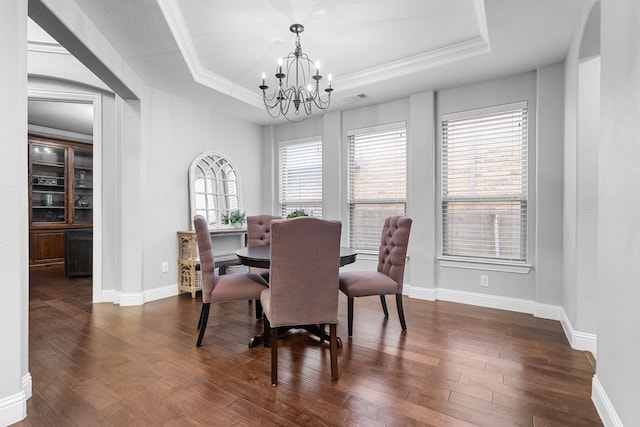 dining space with a raised ceiling, an inviting chandelier, crown molding, and dark hardwood / wood-style floors