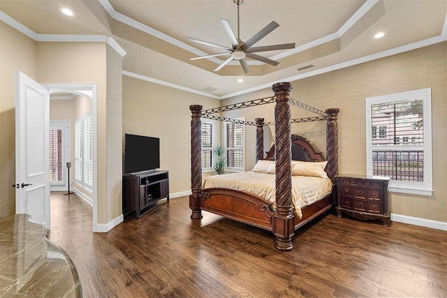 bedroom featuring ceiling fan, dark hardwood / wood-style floors, a tray ceiling, and ornamental molding