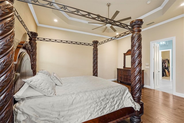 bedroom with wood-type flooring, a tray ceiling, and ornamental molding