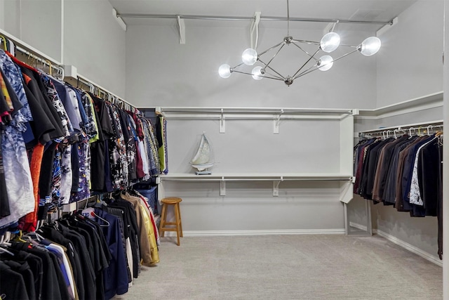 spacious closet with light colored carpet and a notable chandelier