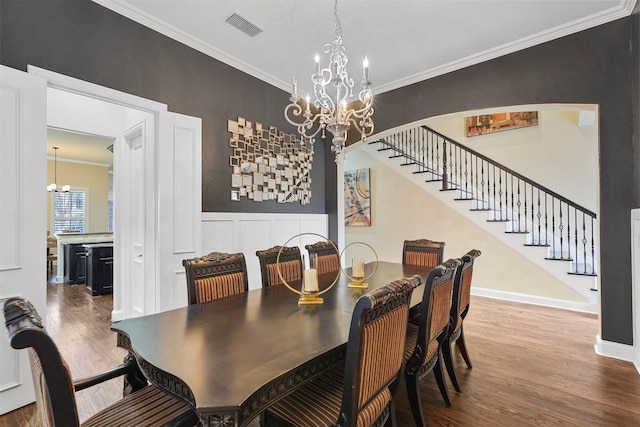 dining space featuring crown molding, wood-type flooring, and a notable chandelier