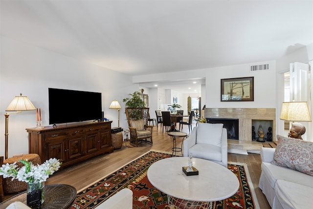 living room with a high end fireplace and light hardwood / wood-style floors