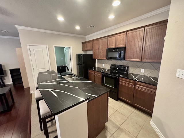 kitchen with sink, a kitchen breakfast bar, black appliances, a kitchen island with sink, and crown molding