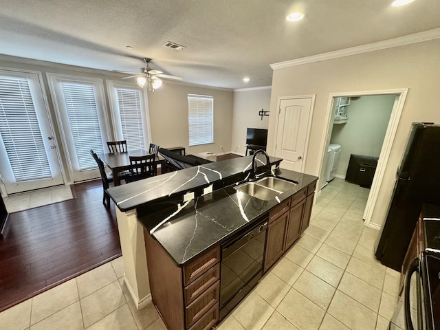 kitchen featuring sink, black appliances, crown molding, and a kitchen island with sink