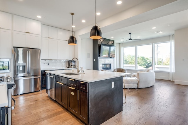 kitchen featuring stainless steel appliances, sink, decorative light fixtures, white cabinetry, and ceiling fan