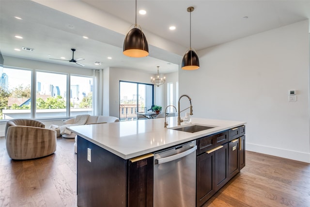 kitchen with stainless steel dishwasher, pendant lighting, an island with sink, ceiling fan with notable chandelier, and sink