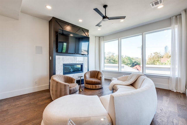 living room with a premium fireplace, ceiling fan, and dark hardwood / wood-style floors