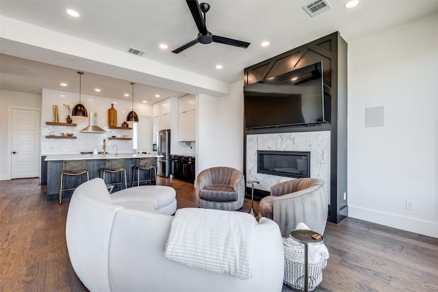 living room with dark hardwood / wood-style flooring, a fireplace, and ceiling fan