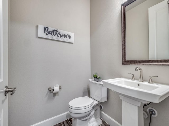 bathroom featuring toilet, sink, and hardwood / wood-style floors