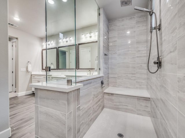 bathroom with tiled shower and vanity