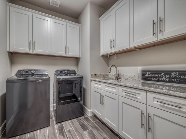 clothes washing area featuring sink, cabinets, and washing machine and clothes dryer